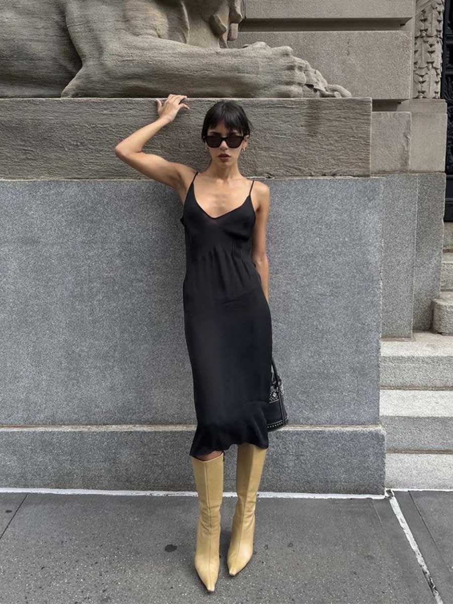 Young woman wearing a black silk midi dress with tall boots