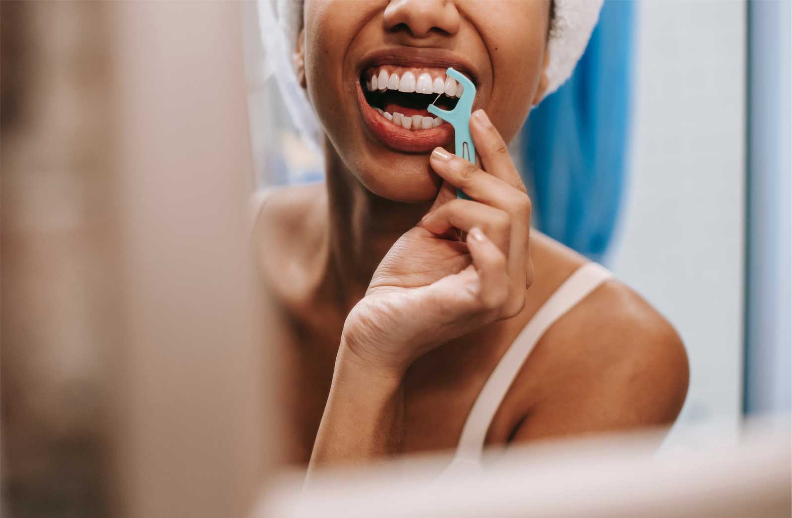 Girl flossing her teeth looking in the mirror–used to illustrate the toxic product, floss