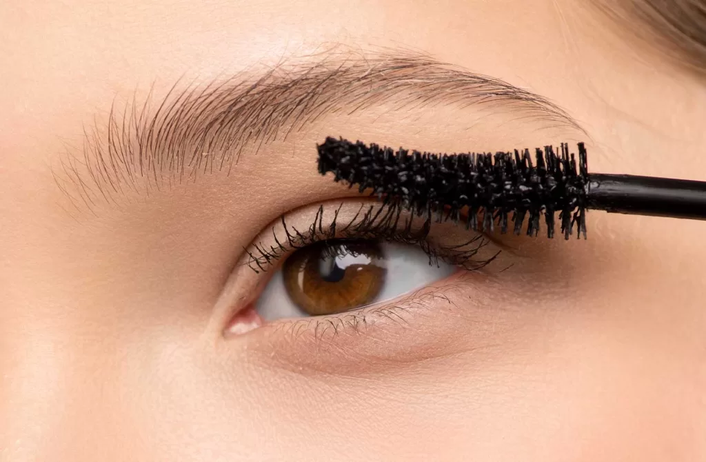 Woman with brown eyes applying mascara