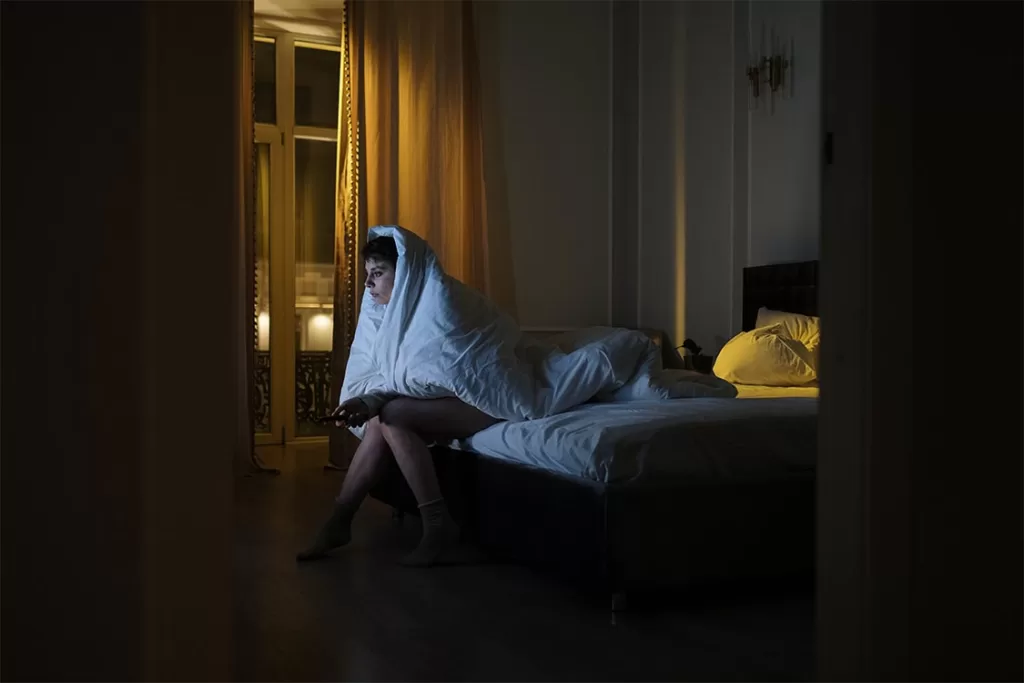 Girl with insomnia watching tv late at night in bed