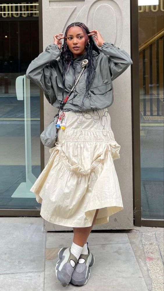 New York City streetstyle shot of a young African American Gen-z woman wearing a maxi skirt with a windbreaker and dad sneakers