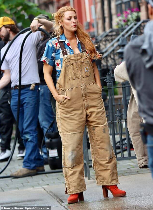 Blake Lively wearing a patchwork shirt under tan carhart overalls with red platform heeled boots as Lily Bloom in movie adaptation of Colleen Hoover's book "It Ends with Us"