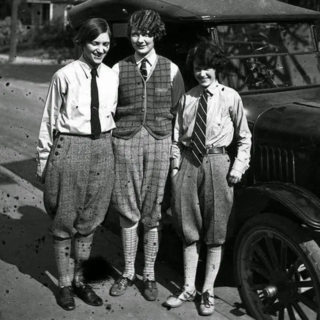 Three young women flappers wearing men's neckties and trousers in the 1920s