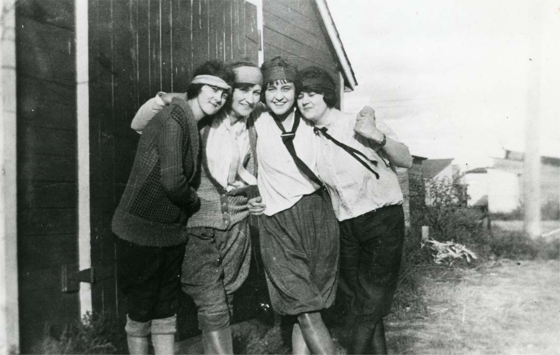 Four young 1920s women flappers wearing ties and trousers